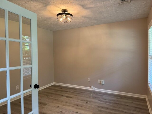 7454 Woody Springs Dr, Flowery Branch, GA 30542 - unfurnished room with wood finished floors, a textured ceiling, baseboards, and french doors