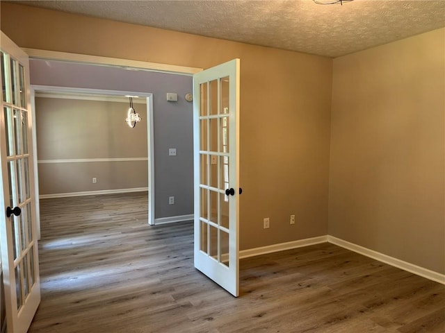 7454 Woody Springs Dr, Flowery Branch, GA 30542 - unfurnished room with french doors, a chandelier, wood finished floors, baseboards, and a textured ceiling