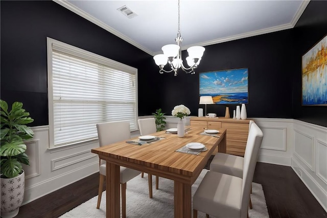 dining room with wood finished floors, a wainscoted wall, visible vents, crown molding, and a chandelier