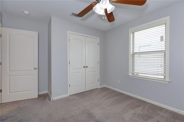 unfurnished bedroom with baseboards, visible vents, carpet floors, ceiling fan, and a closet