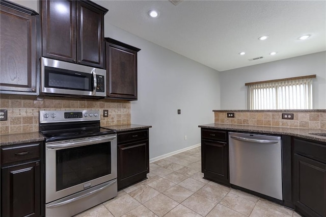 kitchen with baseboards, visible vents, dark stone counters, appliances with stainless steel finishes, and tasteful backsplash