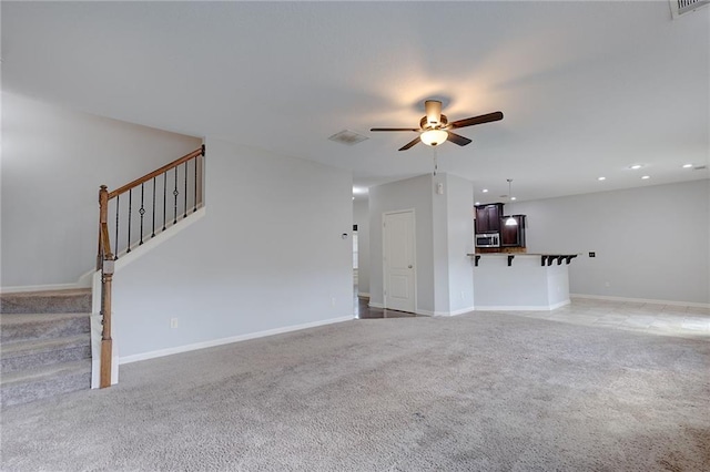 unfurnished living room with light carpet, baseboards, stairs, and ceiling fan