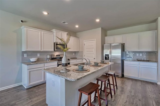 kitchen with wood finished floors, a sink, visible vents, white cabinets, and appliances with stainless steel finishes