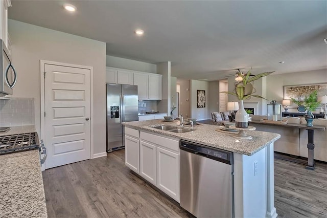 kitchen with white cabinetry, stainless steel appliances, a sink, and open floor plan