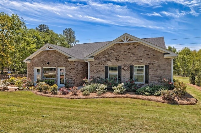 view of front of property featuring roof with shingles, a front lawn, and brick siding