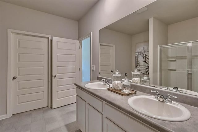 full bathroom featuring double vanity, a shower stall, and a sink