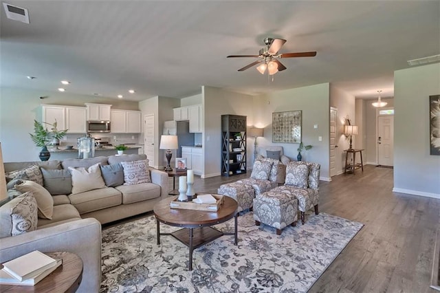 living area with baseboards, visible vents, wood finished floors, and recessed lighting