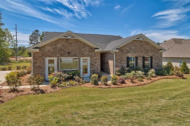 view of front of house featuring a shingled roof, brick siding, and a front lawn