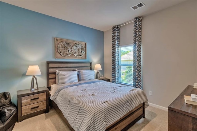 bedroom with baseboards, visible vents, and light colored carpet