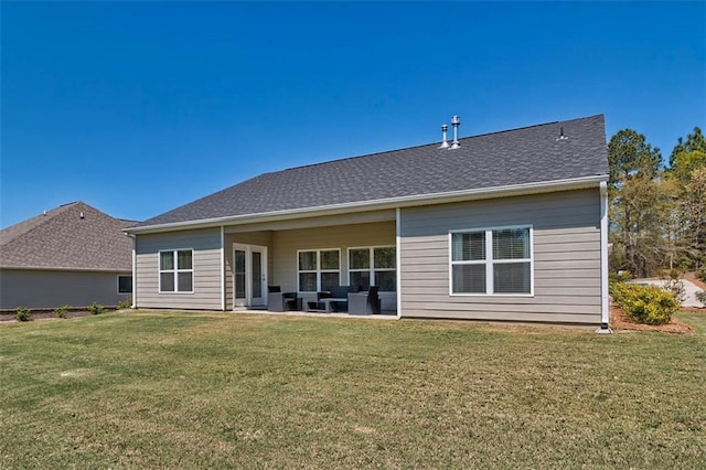 rear view of house featuring a patio, a shingled roof, and a lawn