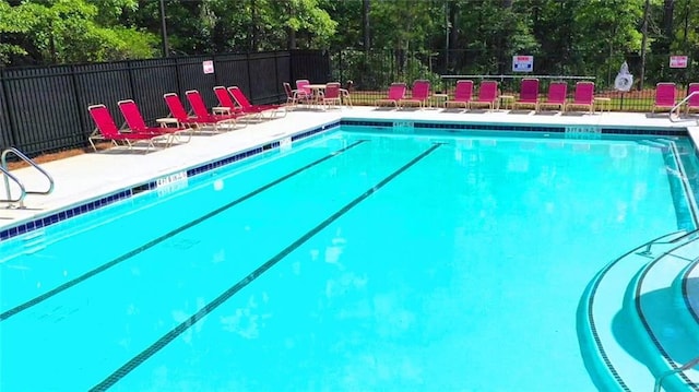 community pool with a patio area and fence