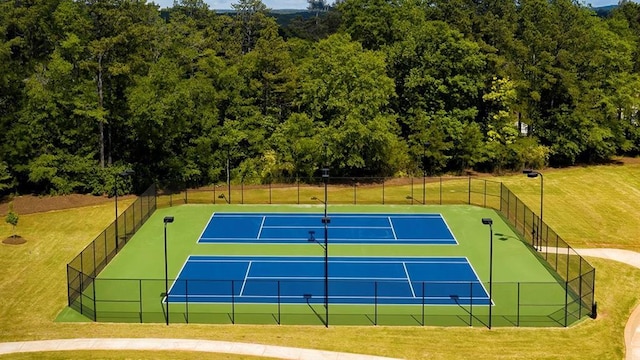 view of sport court featuring fence and a yard