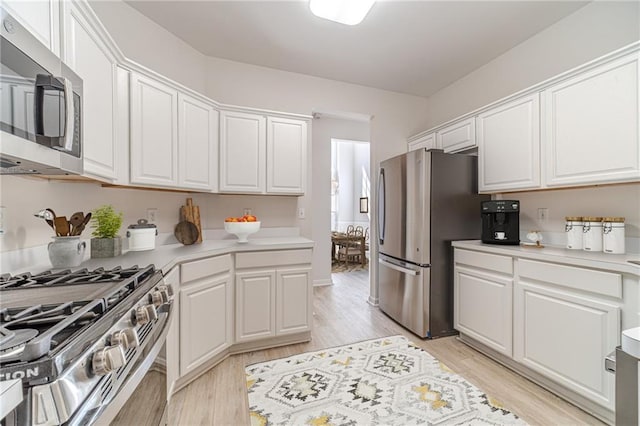 kitchen featuring appliances with stainless steel finishes, light hardwood / wood-style floors, and white cabinets