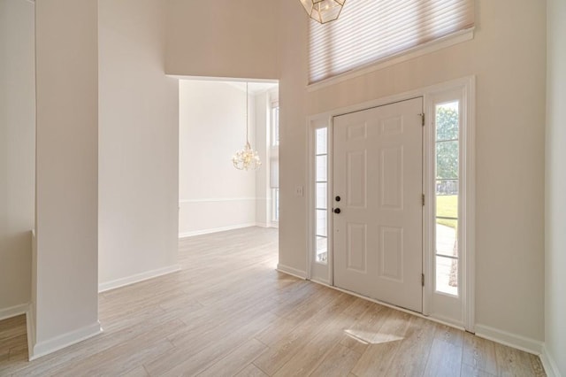 entrance foyer with an inviting chandelier, a high ceiling, and light wood-type flooring