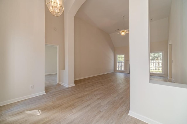 interior space with high vaulted ceiling, ceiling fan with notable chandelier, and light hardwood / wood-style flooring