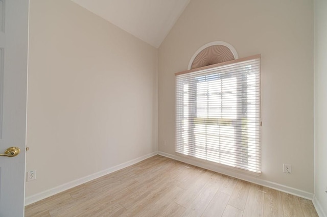 spare room with high vaulted ceiling and light wood-type flooring