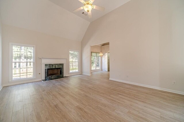 unfurnished living room with ceiling fan, plenty of natural light, a fireplace, and light wood-type flooring