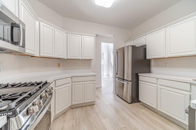 kitchen featuring appliances with stainless steel finishes, light hardwood / wood-style flooring, and white cabinets