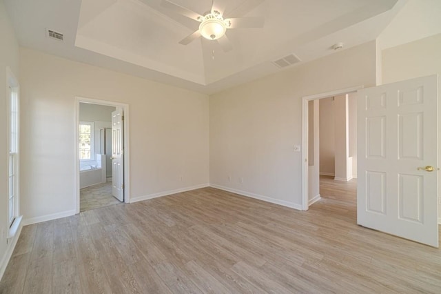 unfurnished room featuring light hardwood / wood-style flooring, ceiling fan, and a tray ceiling