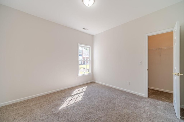 unfurnished bedroom with light carpet, a spacious closet, and a closet