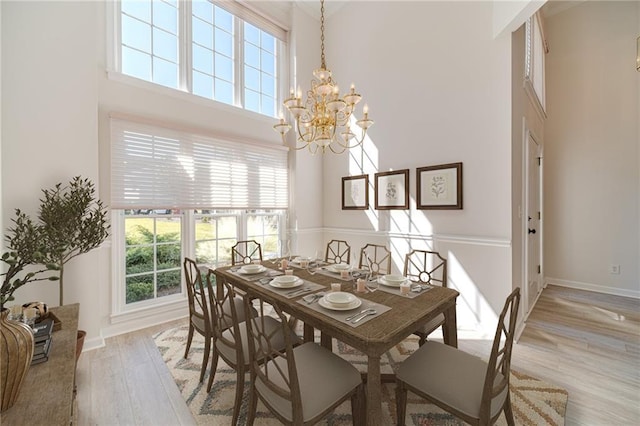 dining space with a high ceiling, a chandelier, and light hardwood / wood-style floors