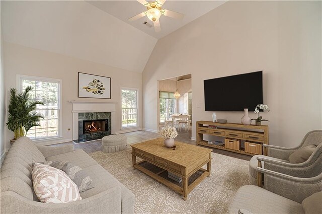 living room featuring high vaulted ceiling, plenty of natural light, hardwood / wood-style floors, and a fireplace