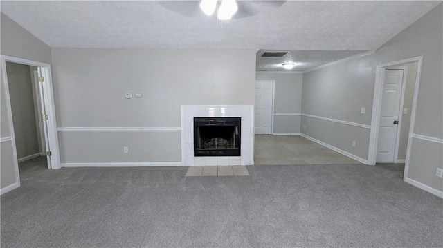 unfurnished living room featuring carpet floors, visible vents, a tiled fireplace, vaulted ceiling, and a textured ceiling