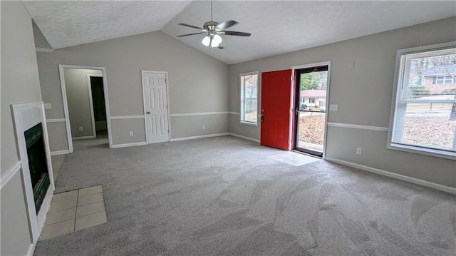 unfurnished living room featuring a healthy amount of sunlight, carpet flooring, and lofted ceiling