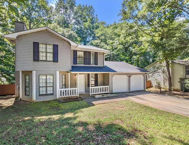 view of front of home featuring covered porch, a garage, and a front lawn