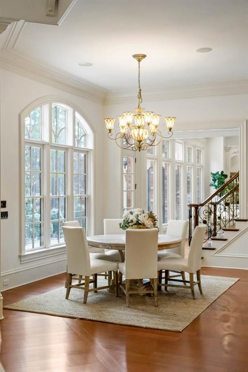 dining room with wood-type flooring, crown molding, a wealth of natural light, and an inviting chandelier