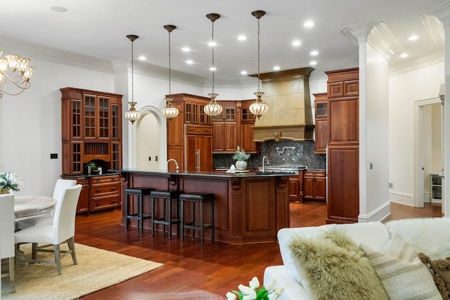 kitchen featuring dark hardwood / wood-style flooring, a center island with sink, pendant lighting, and paneled fridge