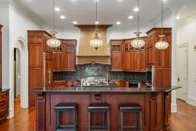 kitchen featuring a kitchen bar, pendant lighting, crown molding, and dark wood-type flooring