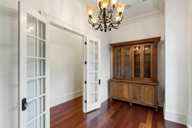 unfurnished dining area featuring a chandelier, crown molding, dark wood-type flooring, and french doors