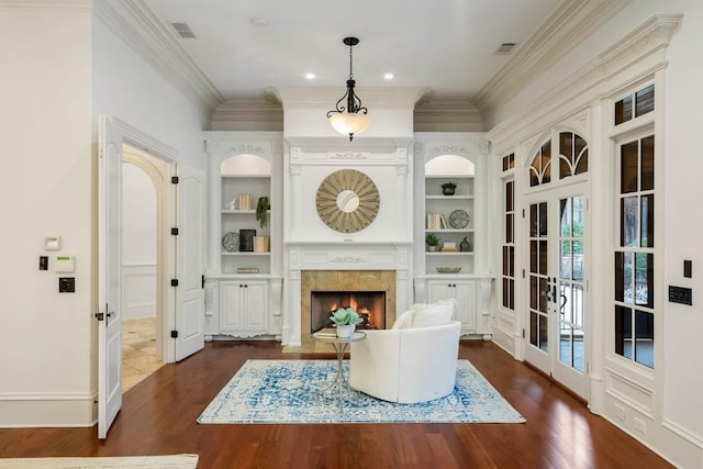 living area featuring a tiled fireplace, french doors, dark wood-type flooring, and ornamental molding