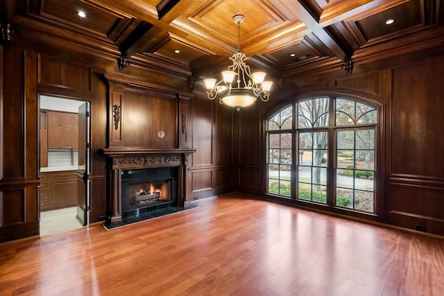 unfurnished living room featuring beamed ceiling, light wood-type flooring, wooden walls, and coffered ceiling