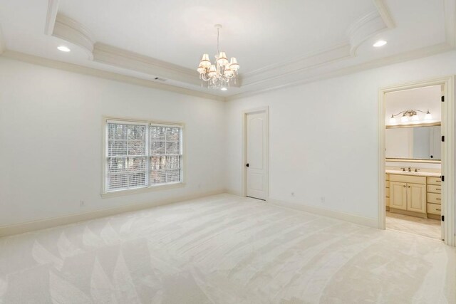 carpeted bedroom featuring a tray ceiling, connected bathroom, crown molding, and a chandelier