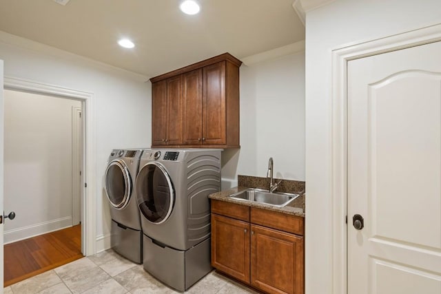 laundry room with sink, cabinets, separate washer and dryer, light hardwood / wood-style floors, and ornamental molding