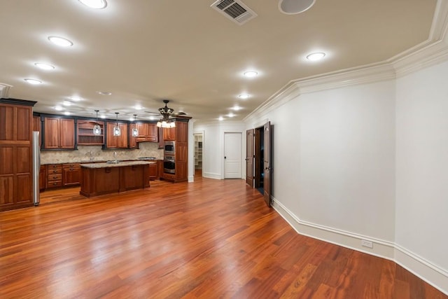 unfurnished living room featuring ceiling fan, wood-type flooring, and ornamental molding