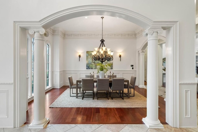 dining area featuring a notable chandelier, wood-type flooring, and ornate columns