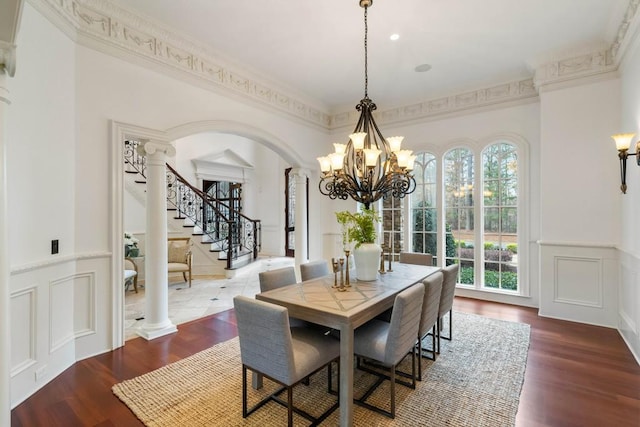 dining room featuring decorative columns, a chandelier, wood-type flooring, and ornamental molding