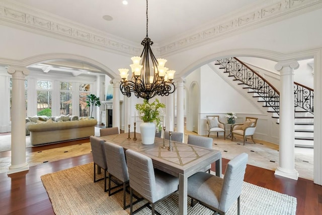 dining area with hardwood / wood-style floors, decorative columns, ornamental molding, and a notable chandelier