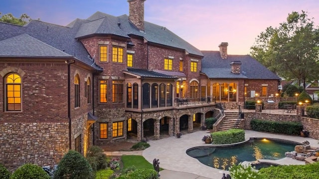 back house at dusk featuring a patio area