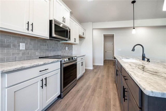 106 Harmony Farms Orch, Eatonton, GA 31024 - kitchen featuring appliances with stainless steel finishes, light wood-type flooring, sink, pendant lighting, and white cabinetry
