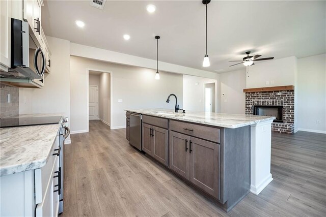 106 Harmony Farms Orch, Eatonton, GA 31024 - kitchen with light stone countertops, hanging light fixtures, hardwood / wood-style floors, an island with sink, and appliances with stainless steel finishes
