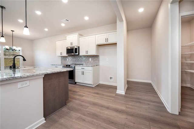 106 Harmony Farms Orch, Eatonton, GA 31024 - kitchen featuring hanging light fixtures, stainless steel appliances, light stone counters, hardwood / wood-style floors, and white cabinets