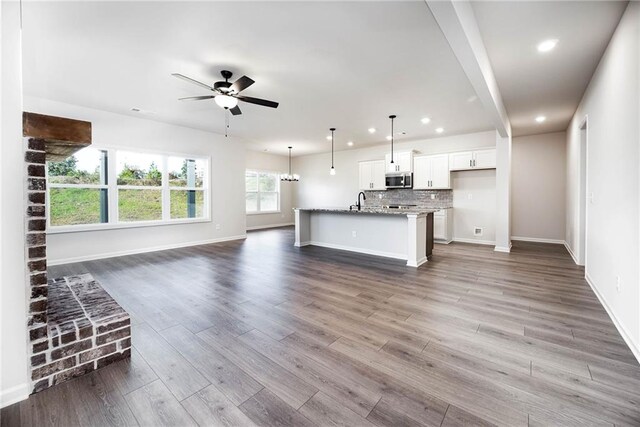 106 Harmony Farms Orch, Eatonton, GA 31024 - unfurnished living room featuring ceiling fan with notable chandelier, dark hardwood / wood-style flooring, and sink