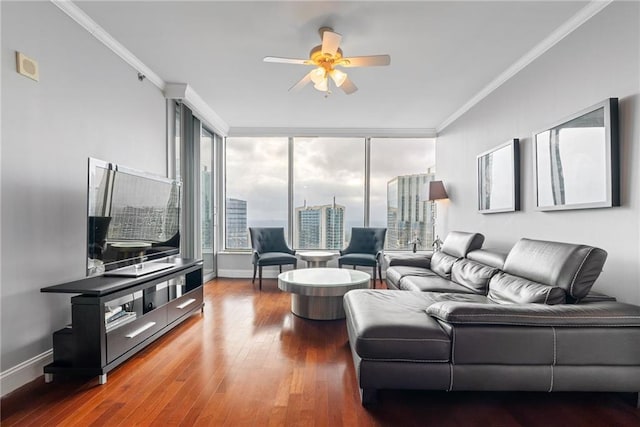 living room featuring baseboards, ceiling fan, ornamental molding, and wood finished floors
