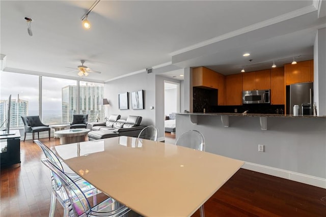 interior space featuring a ceiling fan, dark wood-style flooring, appliances with stainless steel finishes, brown cabinets, and rail lighting
