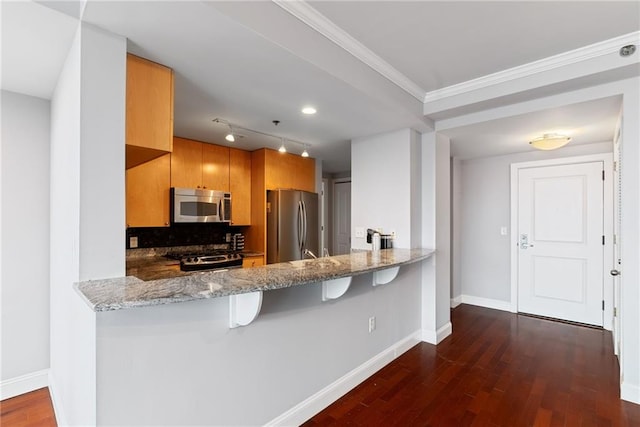 kitchen with stainless steel appliances, light stone countertops, and a peninsula