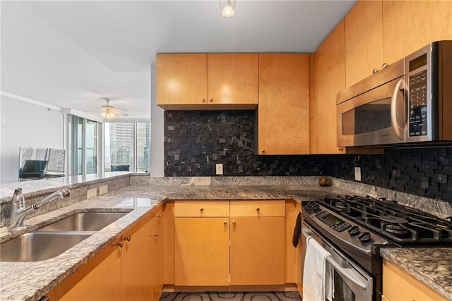 kitchen with a sink, decorative backsplash, a ceiling fan, and stainless steel appliances